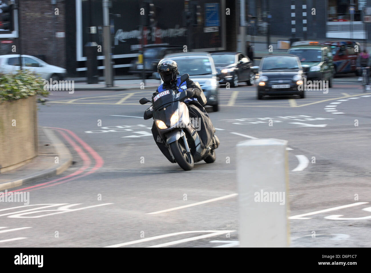 Ein Motorradfahrer (Transport von Blut) und Verkehr Reisen entlang einer Straße (Kreisverkehr) in London, England. Stockfoto