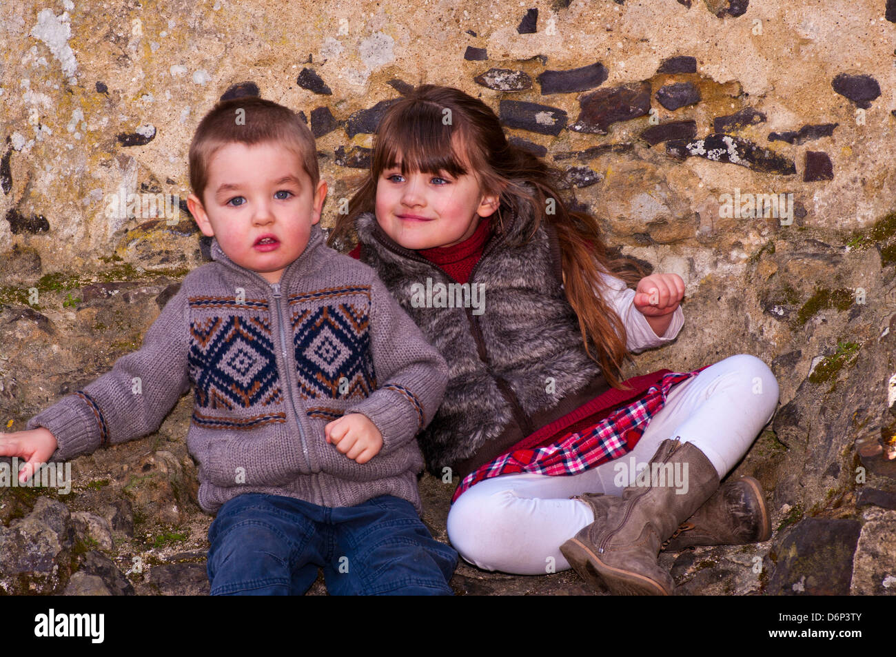 Young Bruder und Schwester gekleidet In warme Kleidung gemeinsam draußen sitzen Stockfoto