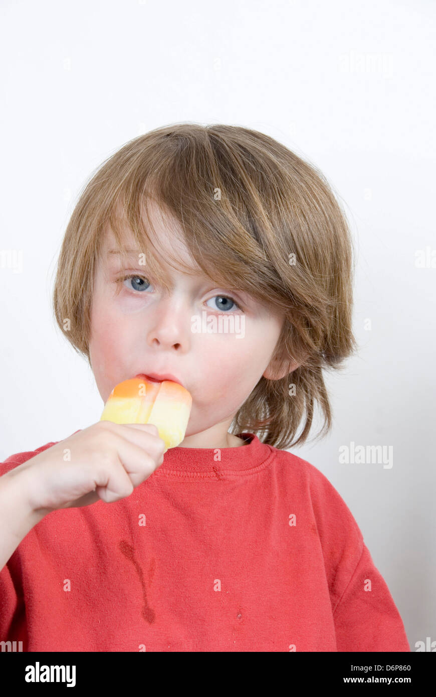 Kleiner Junge saugen an einem bunten Eis am Stiel, Studioportrait isoliert auf weiss Stockfoto