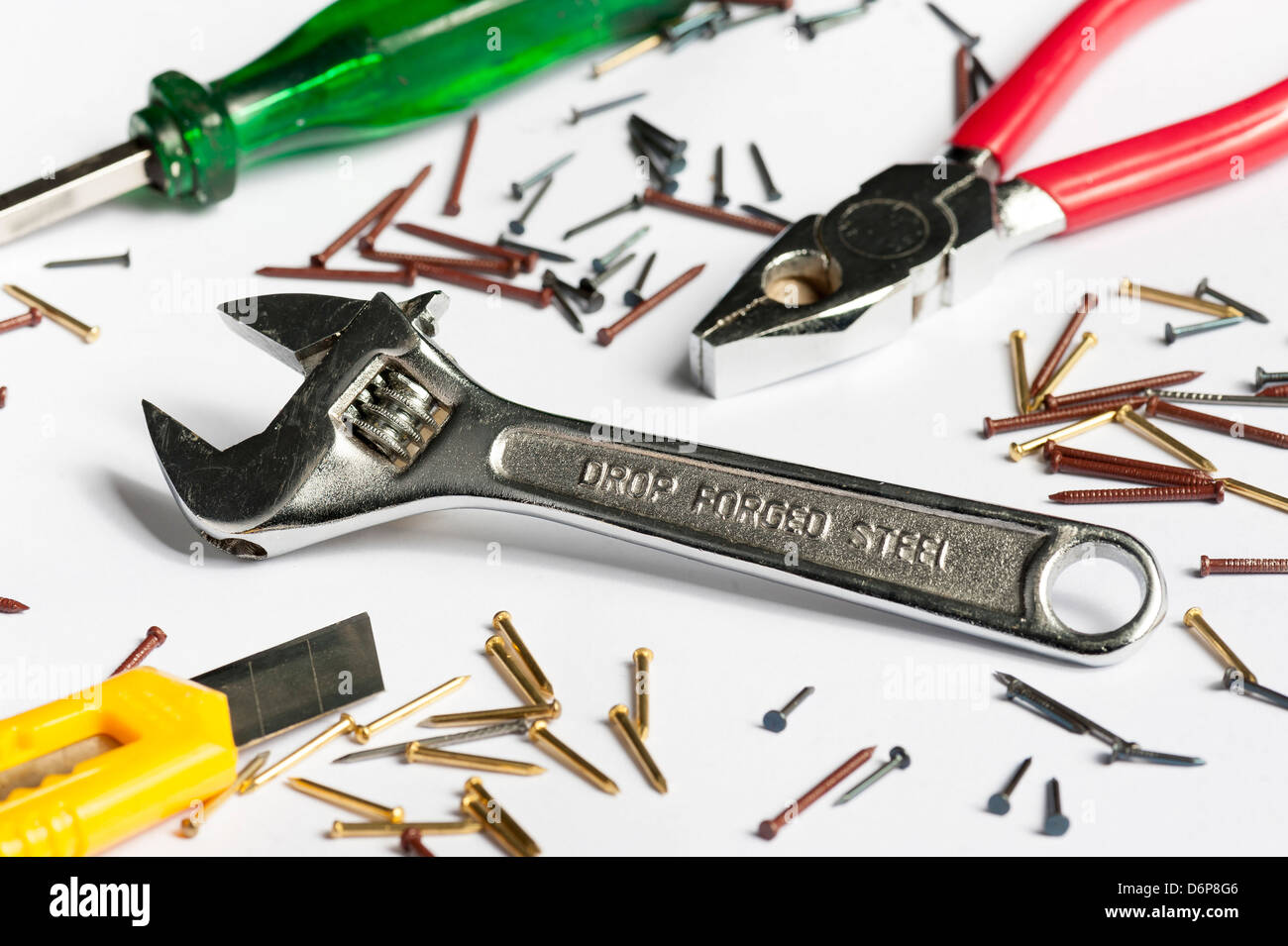 Schraubenschlüssel, Zangen, Schraubenzieher, Stanley-Messer und Nägel auf isolierte weiß. Schraubenschlüssel im Fokus, andere Werkzeuge leicht unscharf Stockfoto