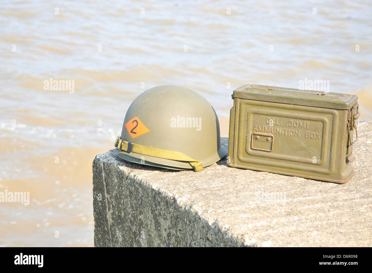 WW2 American Helm und Munition Kasten ruht auf Betonbunker mit Meer im Hintergrund. Stockfoto