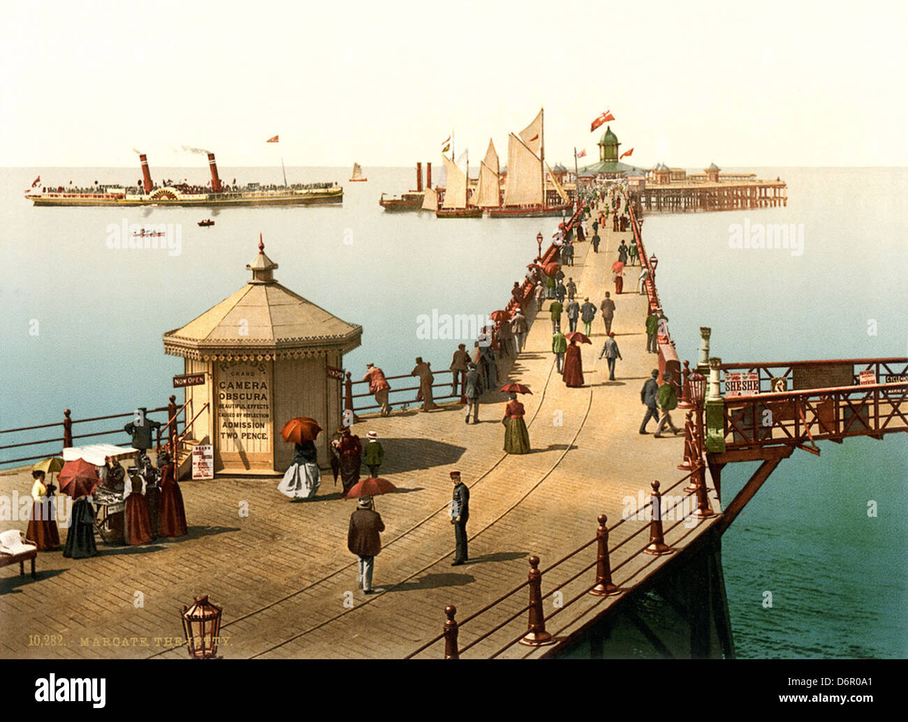 Ein Foto der Anlegestelle in Margate, Kent, England, um 1897. Das Bild fängt die Atmosphäre des Badeortes mit Sonnenschirmen, einem Dampfschiff und einem Segelboot ein, das beliebte Freizeitaktivitäten aus der viktorianischen Zeit repräsentiert. Stockfoto
