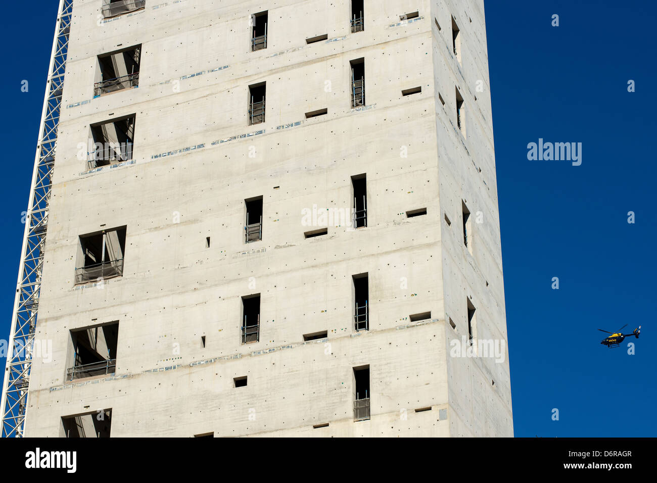 Ein Gebäude im Bau, mit Kran und Polizei-Hubschrauber fliegen in der Nähe umrahmt von einem klaren blauen Himmel Stockfoto