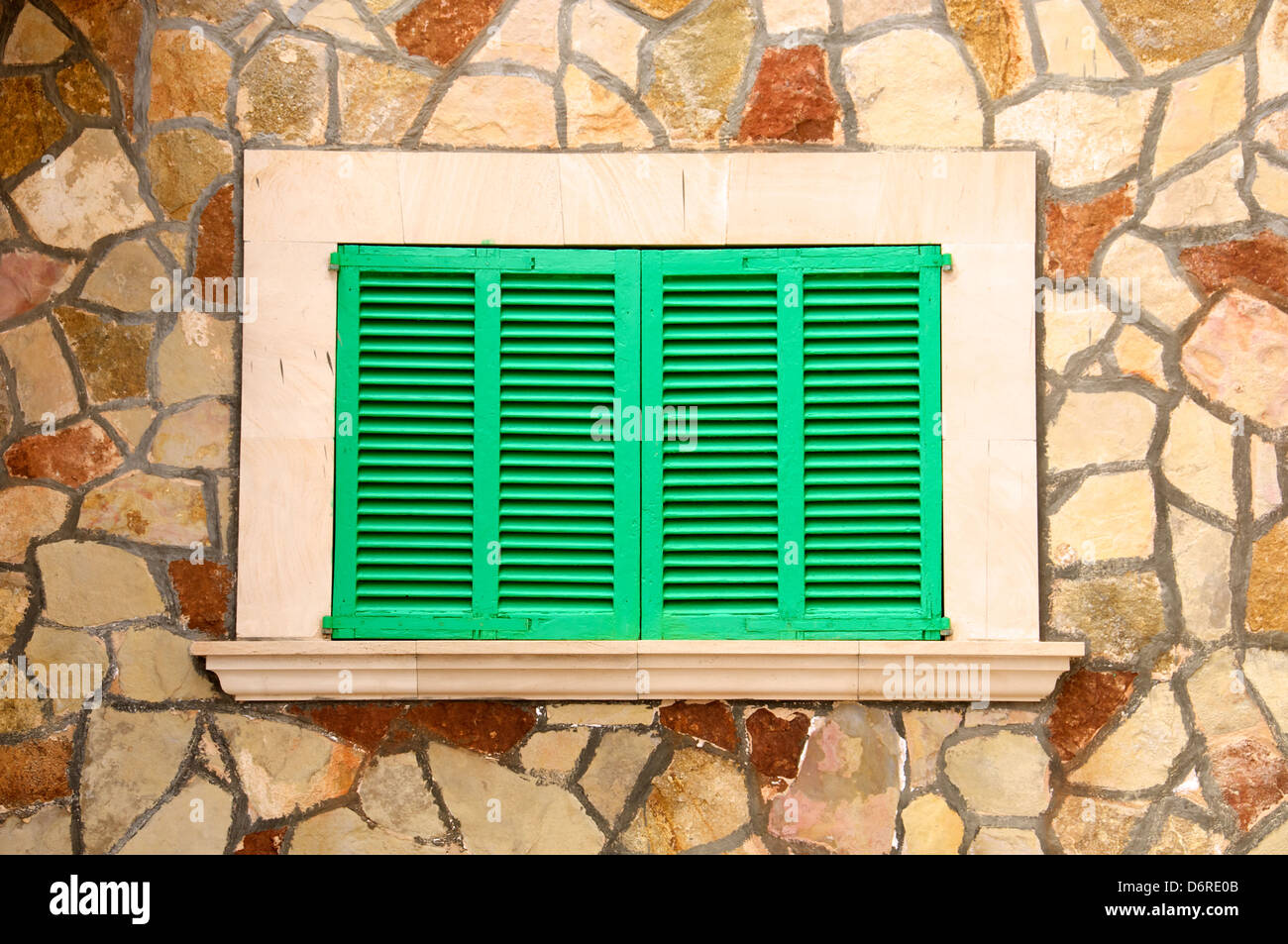 Geschlossenen grünen hölzernen Fensterläden umrahmt von einer Steinmauer umgeben. Stockfoto