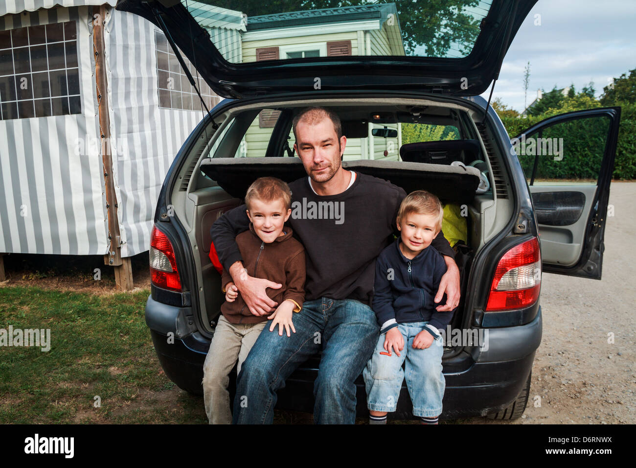 Porträt der Vater zweier Söhne (4-7) sitzen an Rückseite des Auto, Frankreich. Stockfoto
