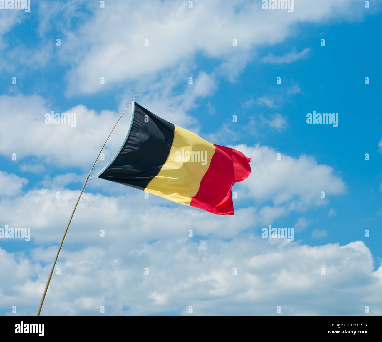 belgische Flagge in eine starke Brise vor einem blauen bewölkten Himmel Stockfoto