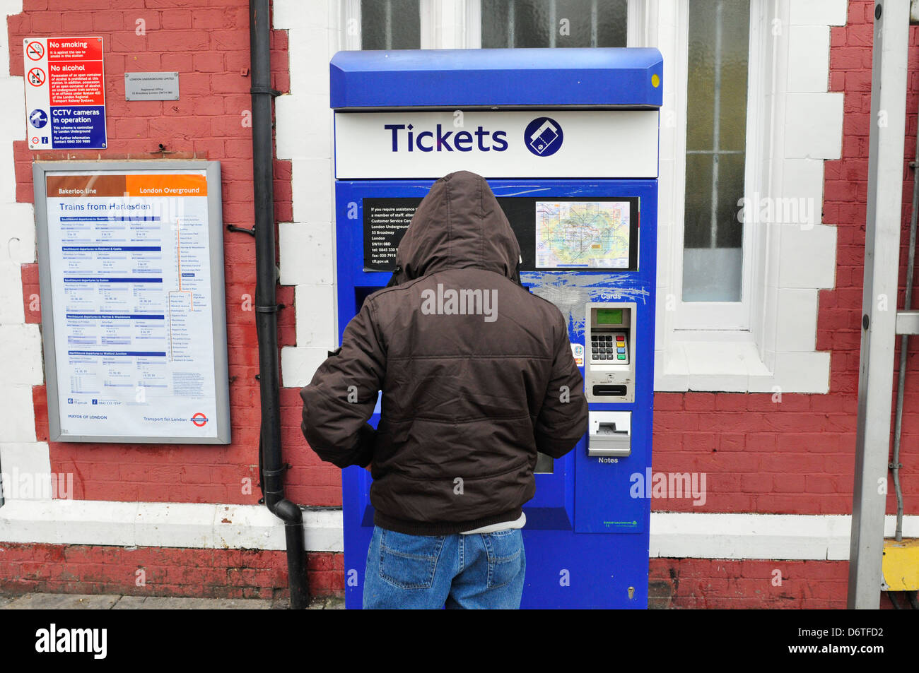 Ein junger Mann nutzt ein Fahrkartenautomat am Bahnhof Harlesden, London, UK Stockfoto