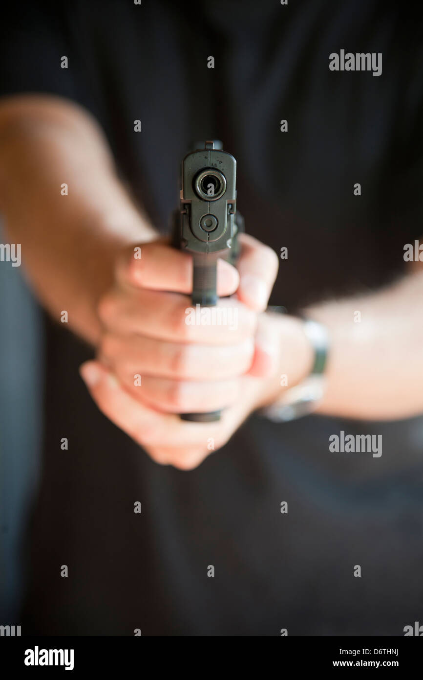 Junger Mann zeigte auf Kamera mit einer Pistole. Selektiven Fokus an der Pistole. Stockfoto