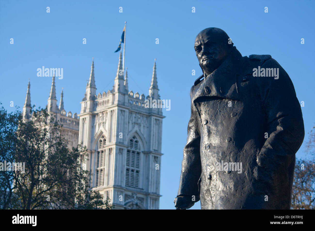 Statue von Sir Winston Churchill im Parliament Square mit Türmen der Westminster Abbey in London England UK Hintergrund Stockfoto