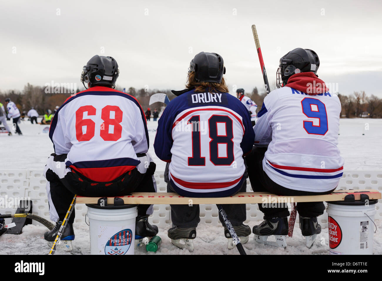 Teich-Hockey-Spieler sehen die Aktion von der Mannschaftsbank während eines Spiels bei der US-Pond Hockey Meisterschaften auf See Nokomis. Stockfoto