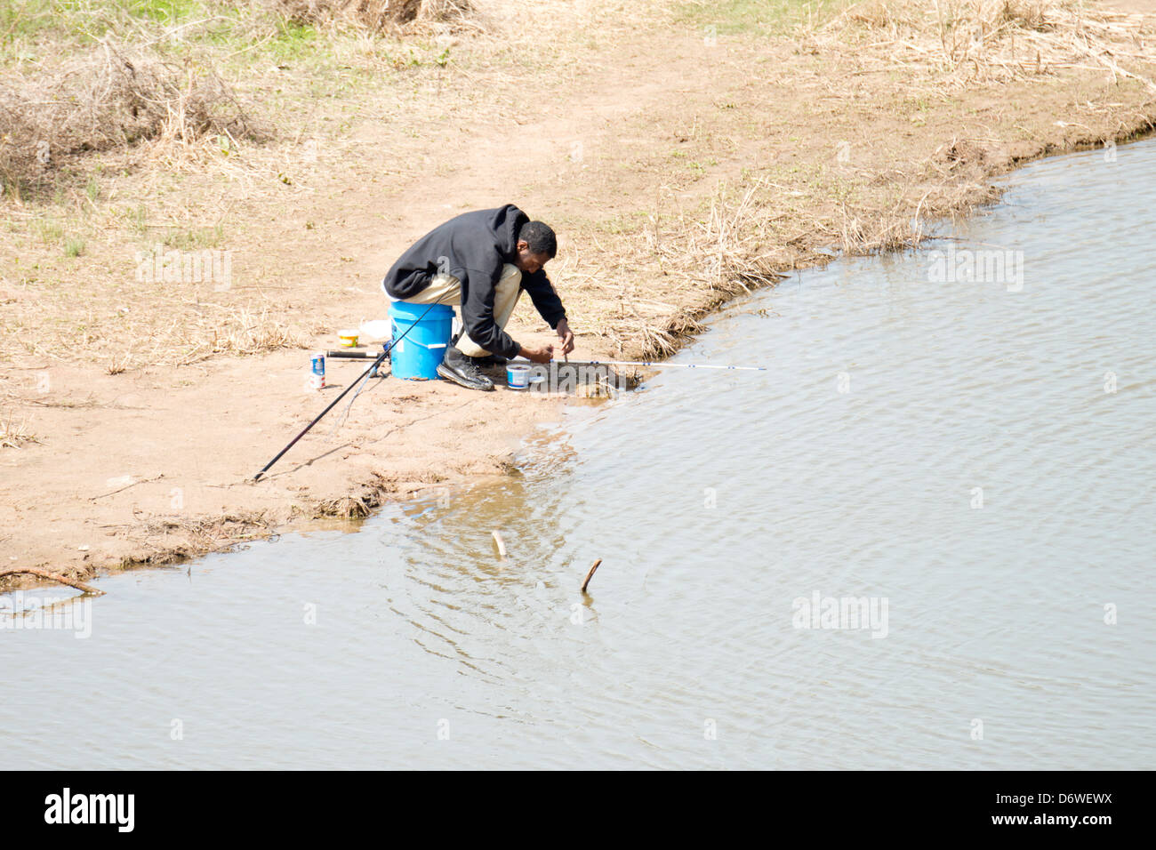 Eine junge schwarze Mann Köder seine Haken Fisch im Norden der Kanadischen Fluss unten Overholser Damm in Oklahoma City, Oklahoma, USA im zeitigen Frühjahr. Stockfoto