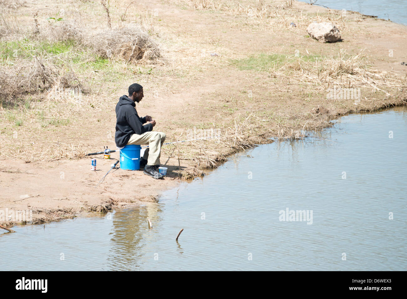 Eine junge schwarze Mann Köder seine Haken Fisch im Norden der Kanadischen Fluss unten Overholser Damm in Oklahoma City, Oklahoma, USA im zeitigen Frühjahr. Stockfoto
