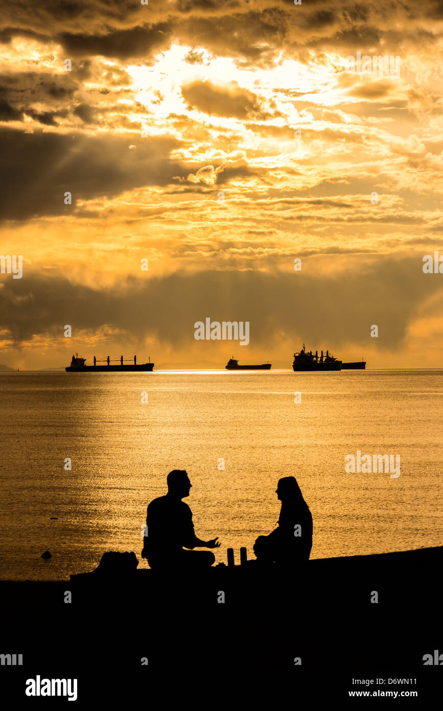 Silhouette zu zweit am English Bay bei Sonnenuntergang, Vancouver, Britisch-Kolumbien, Kanada Stockfoto