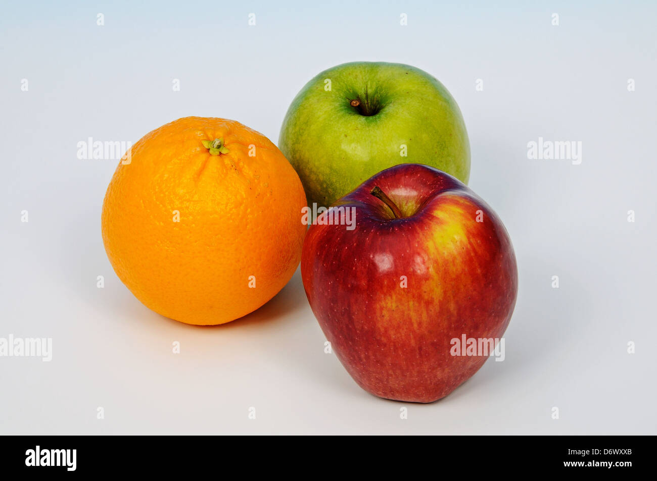 Zwei Äpfel und Orange auf einem einfachen Hintergrund. Stockfoto