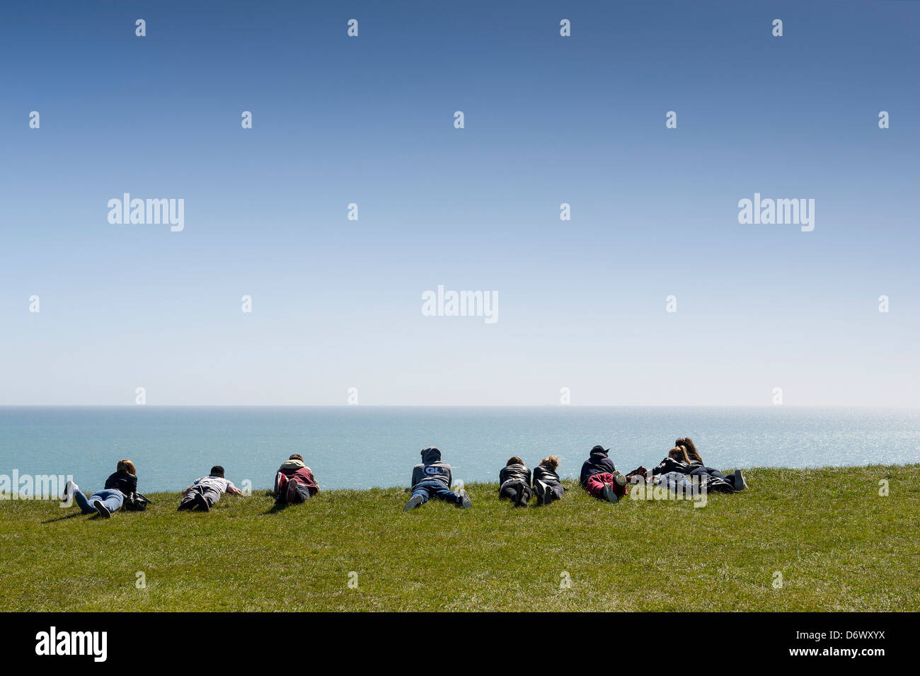 Eine Gruppe von jungen Menschen auf der Suche über den Rand einer Klippe in der Nähe von Beachy Head. Stockfoto