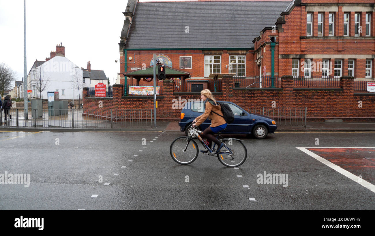 Junge Frau, Radfahrerin und Auto an Fußgängerübergangsampeln, die an der St Monica's School in Cathays Cardiff Wales, Großbritannien, VORBEIFAHREN, KATHY DEWITT Stockfoto