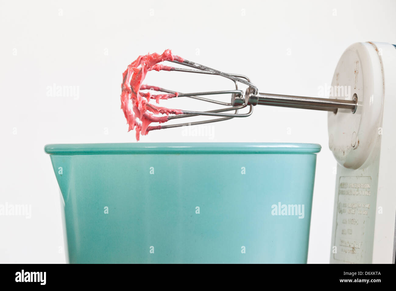 elektrischen Mixer mit rosa/roten Zuckerguss auf den Schläger mit einer blauen Schüssel, Stockfoto
