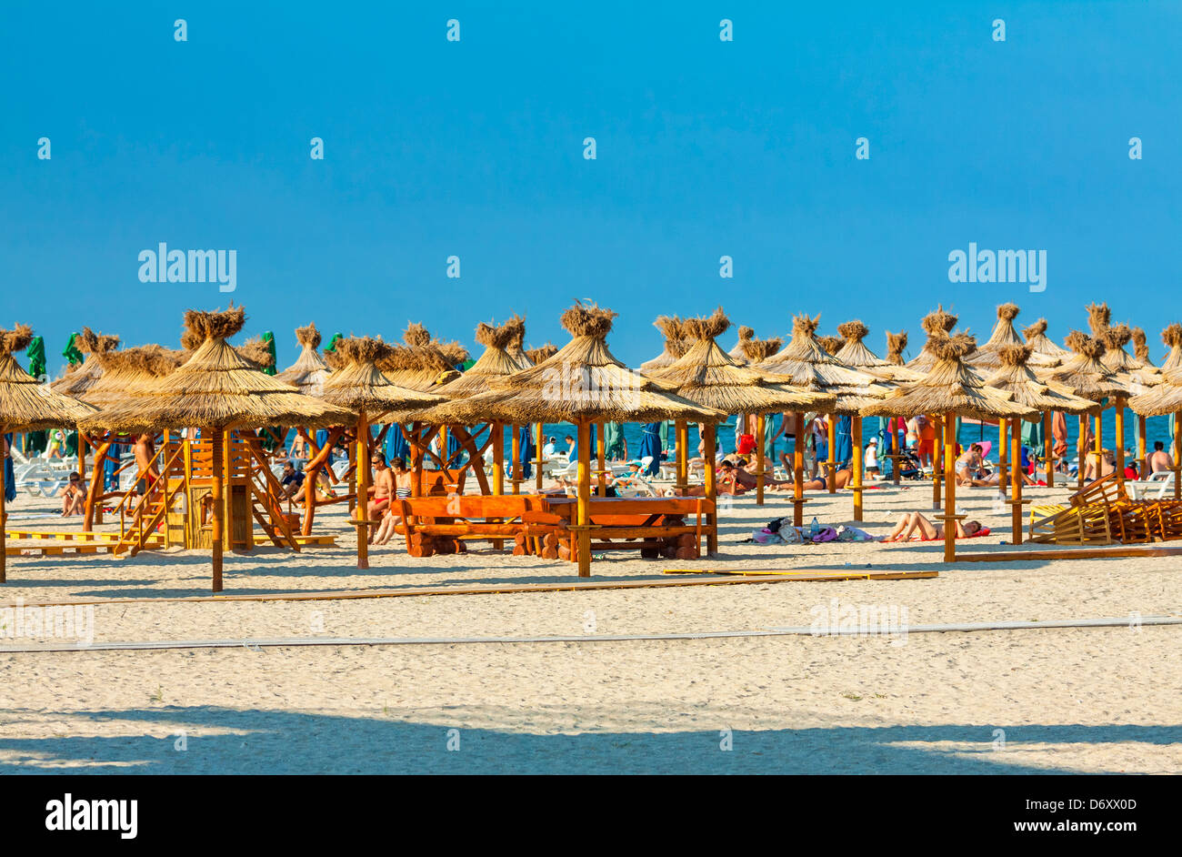 MAMAIA, Rumänien - 5. AUGUST: Touristen Sonnen und Rest unter Reed Sonnenschirme am Strand am 5. August 2011 in Mamaia, Rumänien. Stockfoto