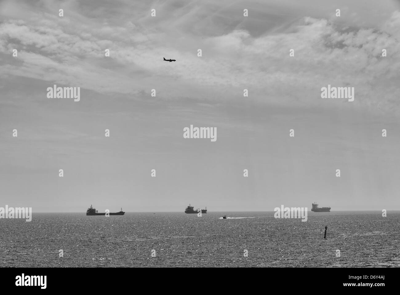 Boote und Flugzeug auf dem Meer, mit Wolken. Schwarz & weiß Stockfoto