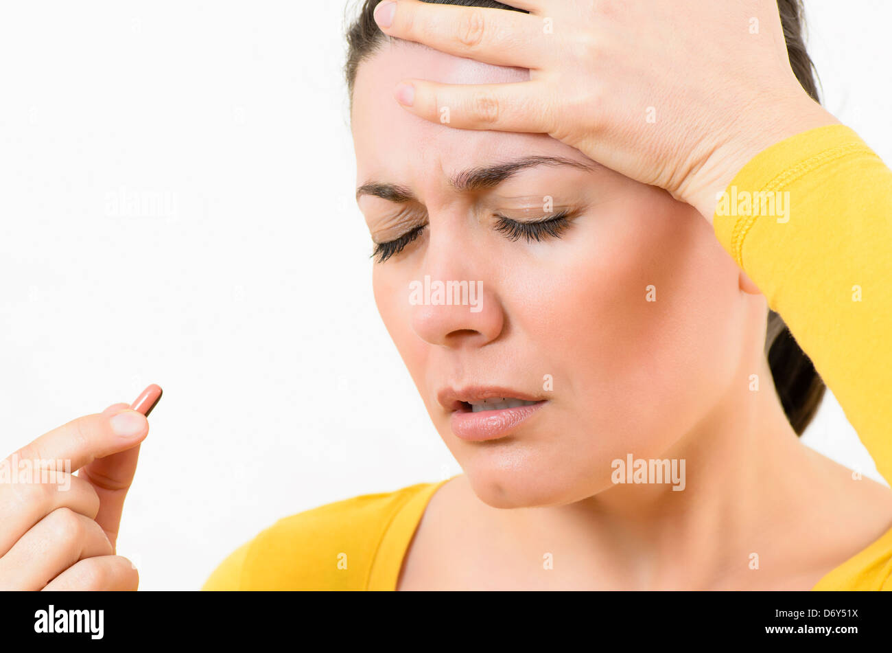 Junge Frau, die mit einer Pille Kopfschmerzen Stockfoto