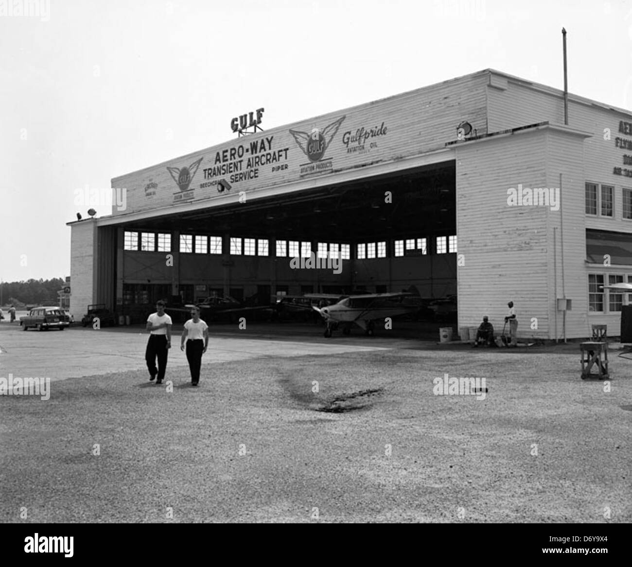 Dieses Foto zeigt den Aero-Way Transient Aircraft Service Hangar an einem Flughafen in Richmond, Virginia, das 1955 aufgenommen wurde. Es zeigt die modernistische Architektur des Gebäudes und die angebotenen Flugdienste. Stockfoto