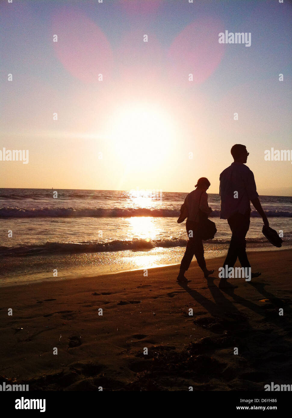 Silhouette eines Paares zu Fuß am Strand bei Sonnenuntergang Stockfoto
