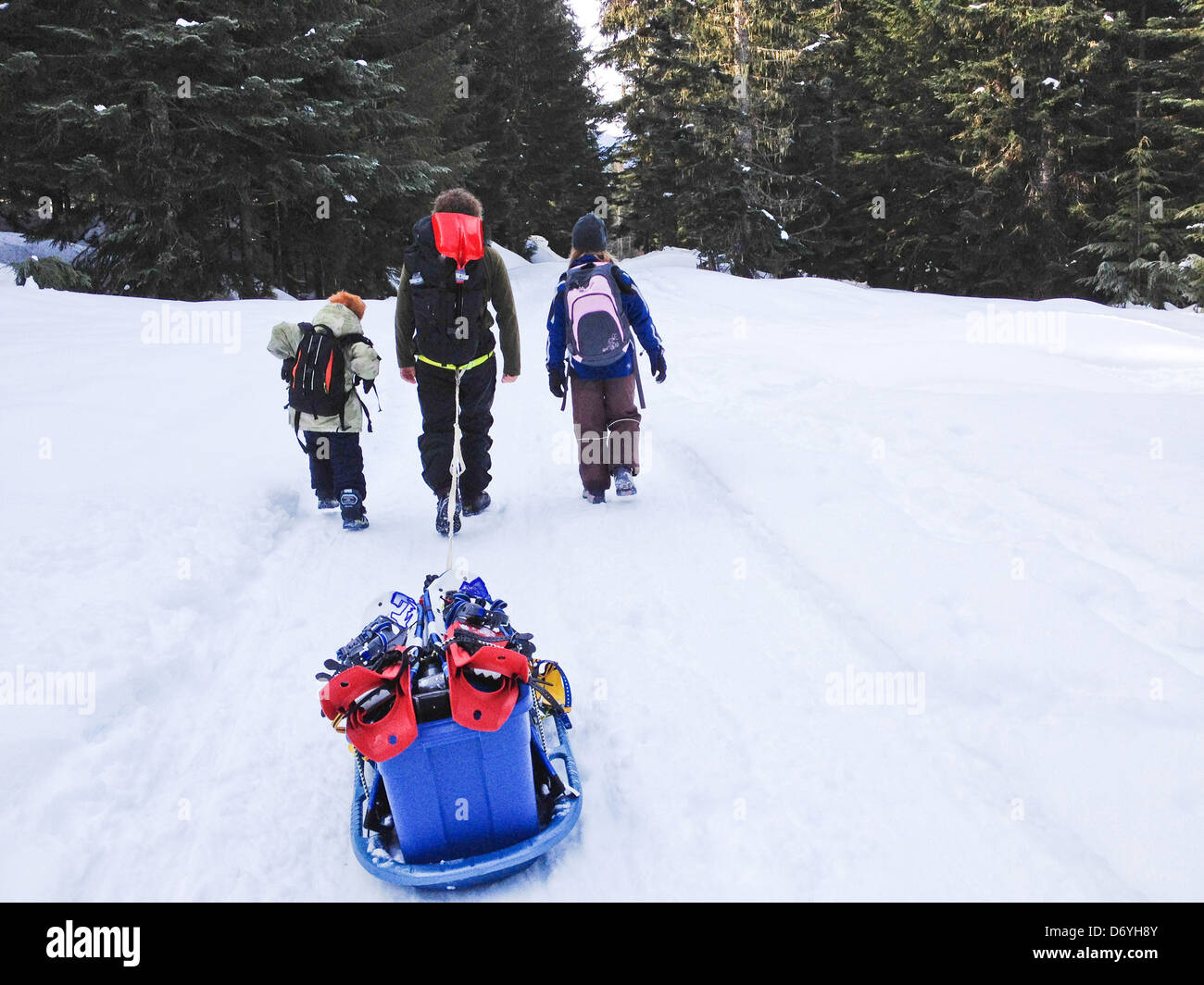 Kaukasische Familie zieht Schlitten durch Schnee - Smartphone-aufgenommenes Stockfoto