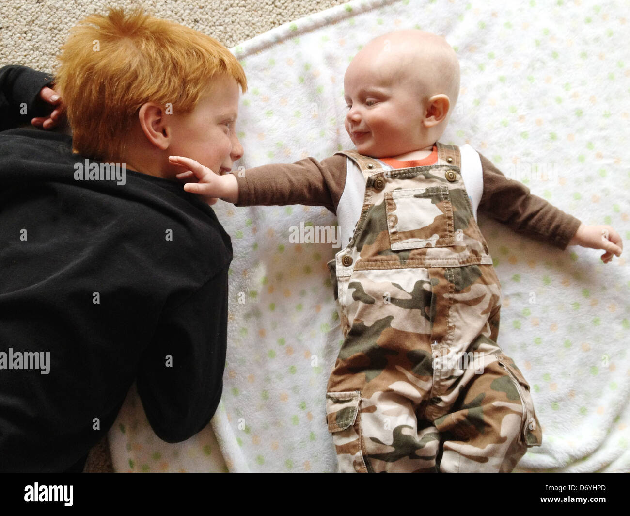 Kaukasische junge Blick auf kleinen Bruder - Smartphone-aufgenommenes Stockfoto
