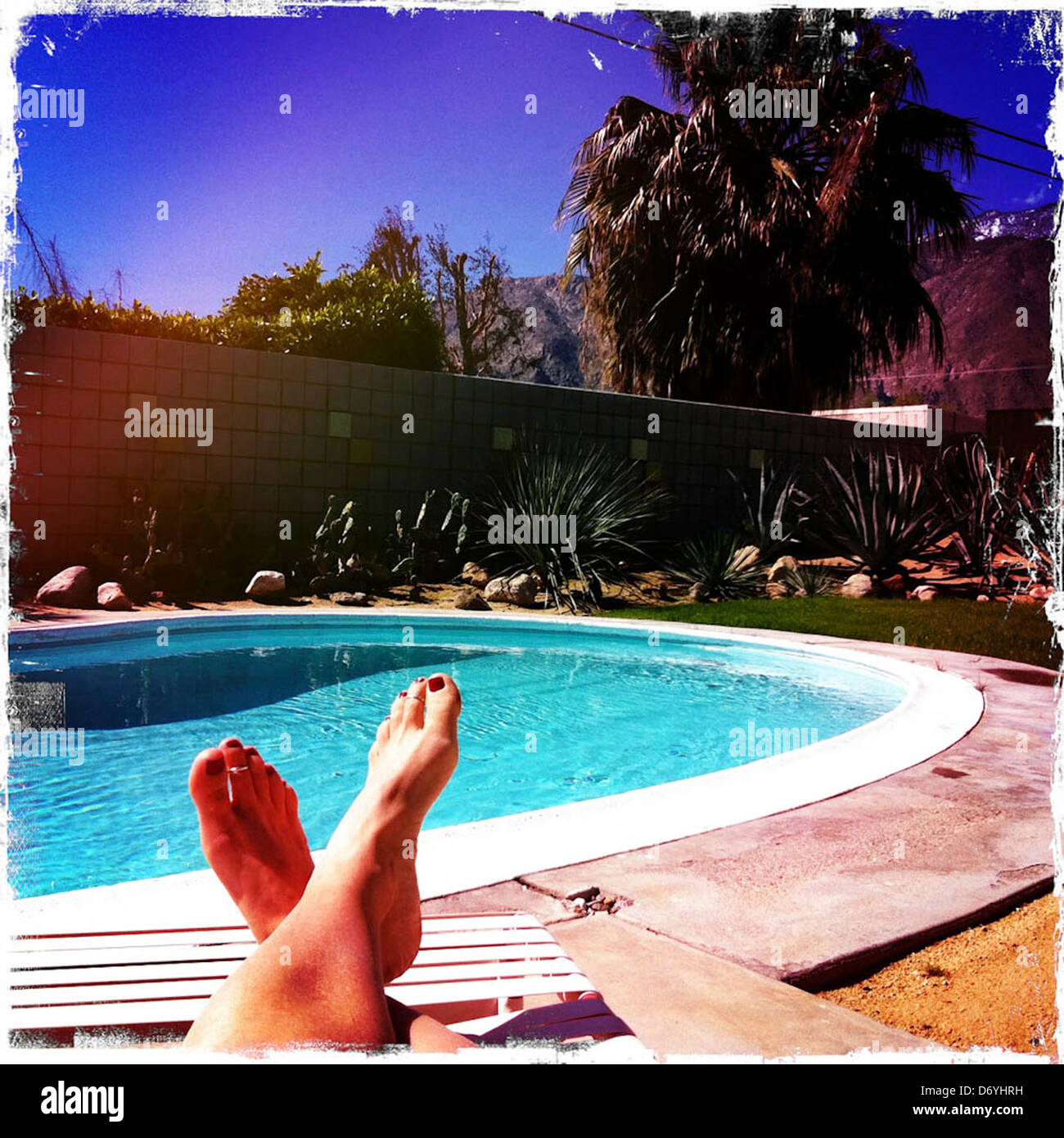 Kaukasische Frau Sonnenbaden am Pool - Smartphone-aufgenommenes Stockfoto