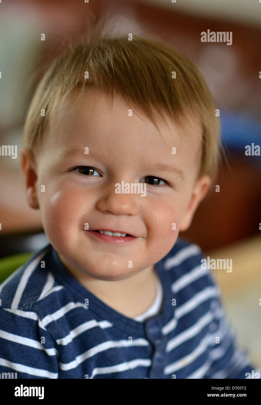 Ein Foto von lächelnden Kleinkind im Alter von achtzehn Monate alt, mit braunen Haaren tragen eine blaue und weiße abgespeckte t-Shirt. Stockfoto