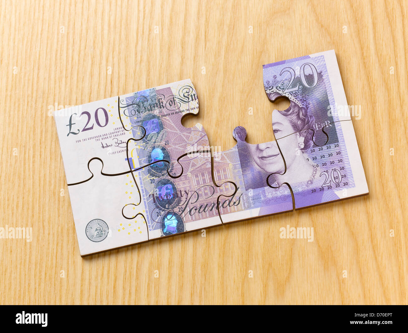 Britische Währung 20-Pfund-Note, Puzzle mit einem Stück fehlt, auf hölzernen Schreibtisch Stockfoto