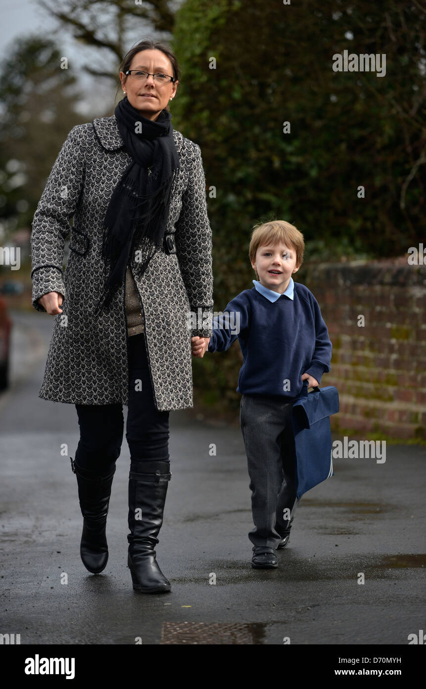 Ein fünf Jahre alter Junge tragen Schuluniform, mit seiner Mutter in die Schule gehen. Stockfoto