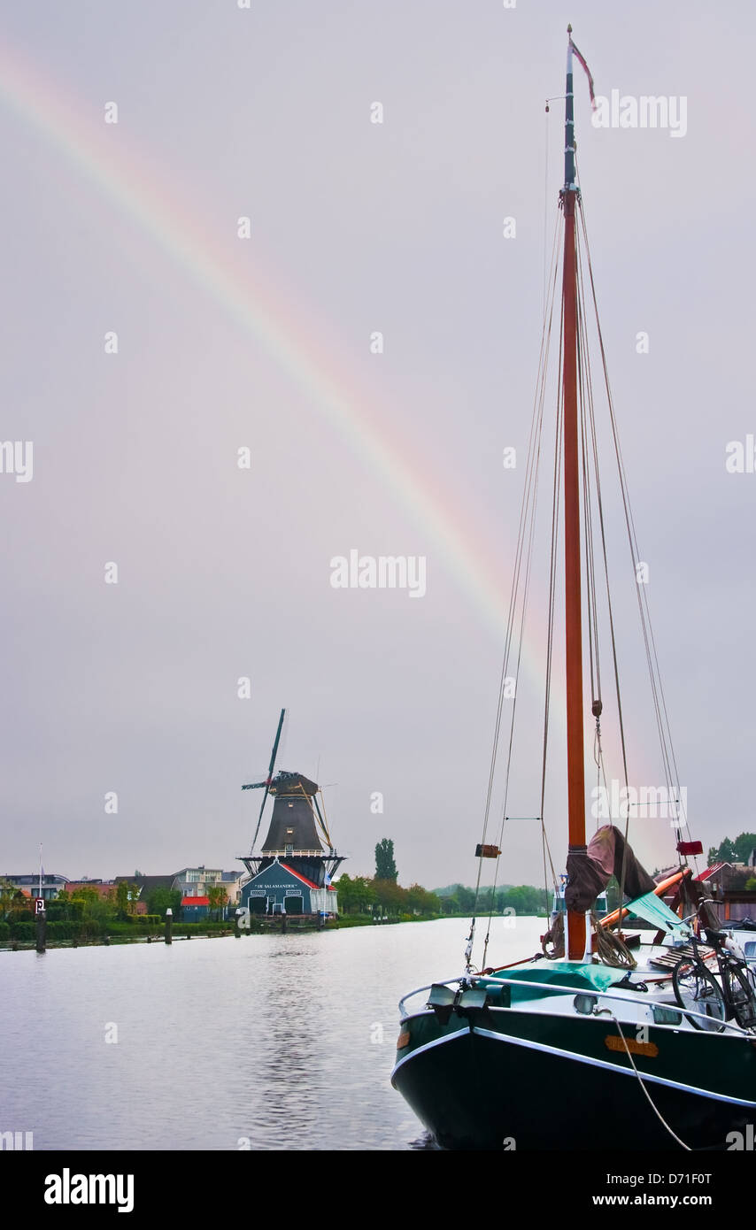 Alte Sägerei oder Bauzeiten mit Schiff und Regenbogen in den Niederlanden an regnerischen Tag im Frühling Stockfoto