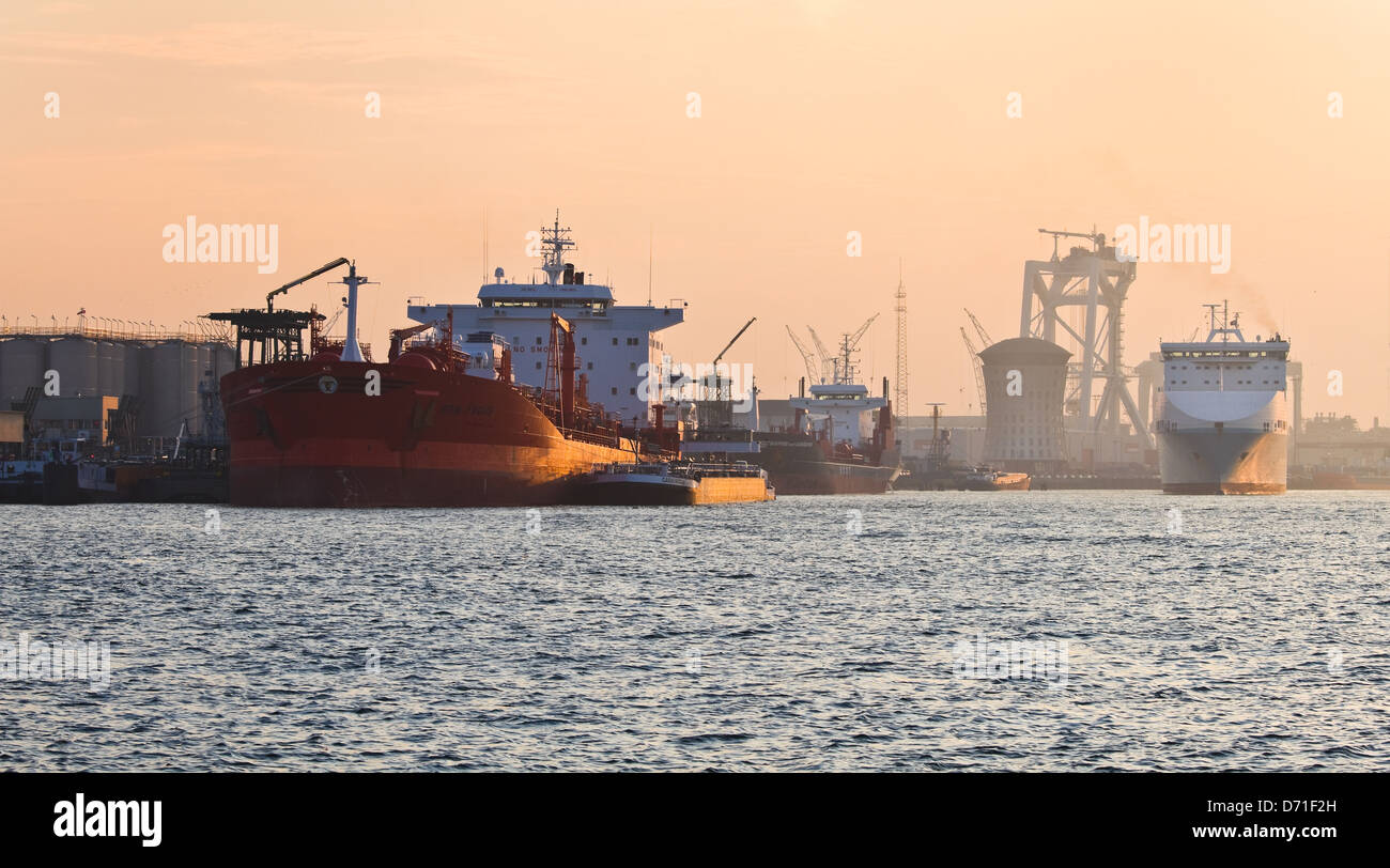 Tanker im Hafen bei roter Sonnenaufgang mit industriellem Hintergrund Rotterdam, Niederlande Stockfoto