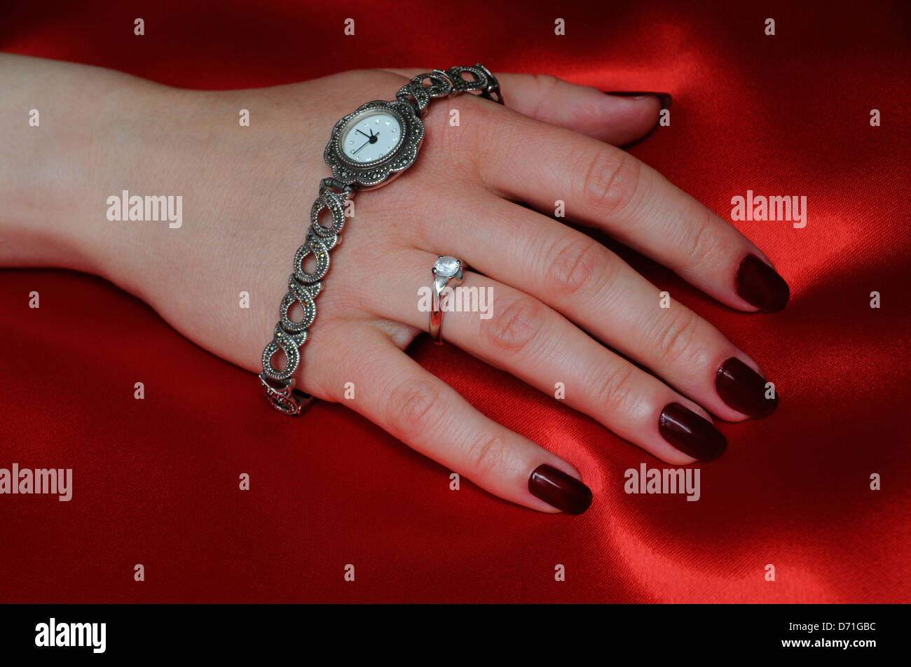 Feminine Armbanduhr und Hand auf rotem satin. Stockfoto