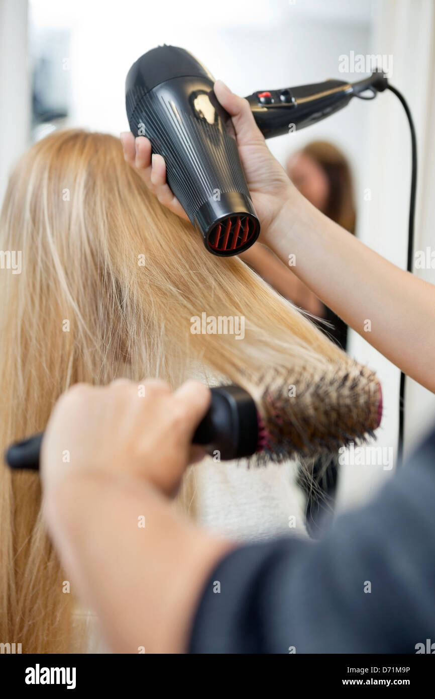 Trocknen das Haar der Frau im Friseursalon Stylistin Stockfoto