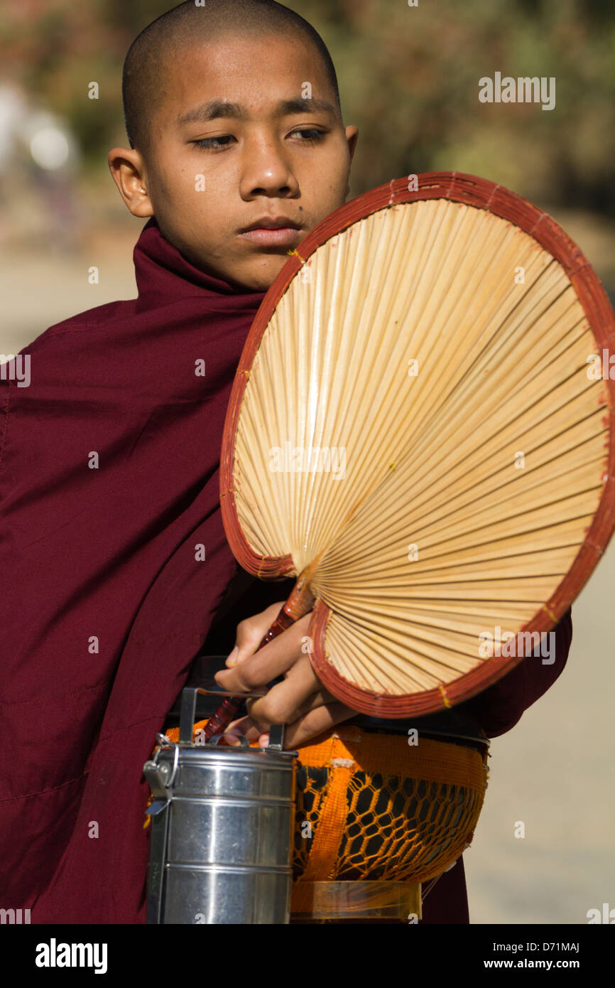 Novize mit Ventilator, Lunchbox und Sammlung Schüssel in Bagan, Myanmar Stockfoto