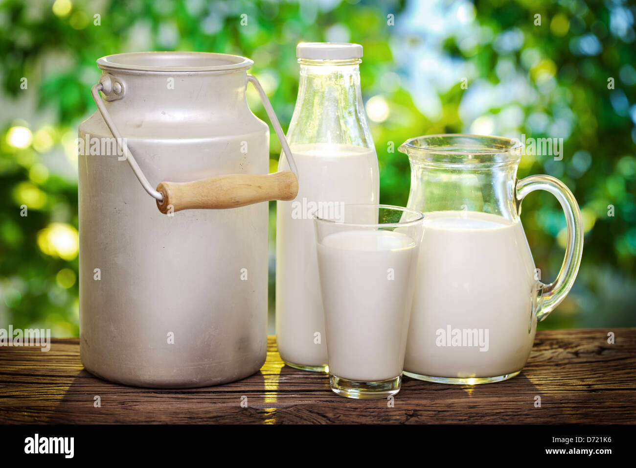 Milch in verschiedenen Gerichten auf dem alten Holztisch im Freien. Stockfoto