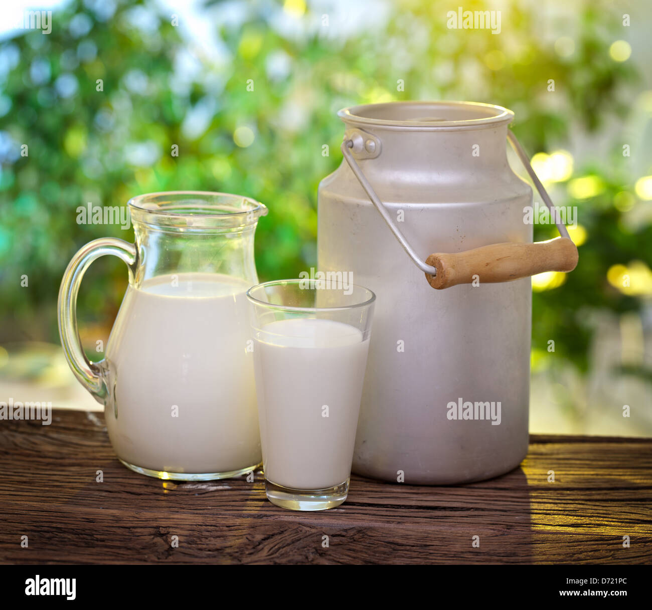 Milch in verschiedenen Gerichten auf dem alten Holztisch im Freien. Stockfoto