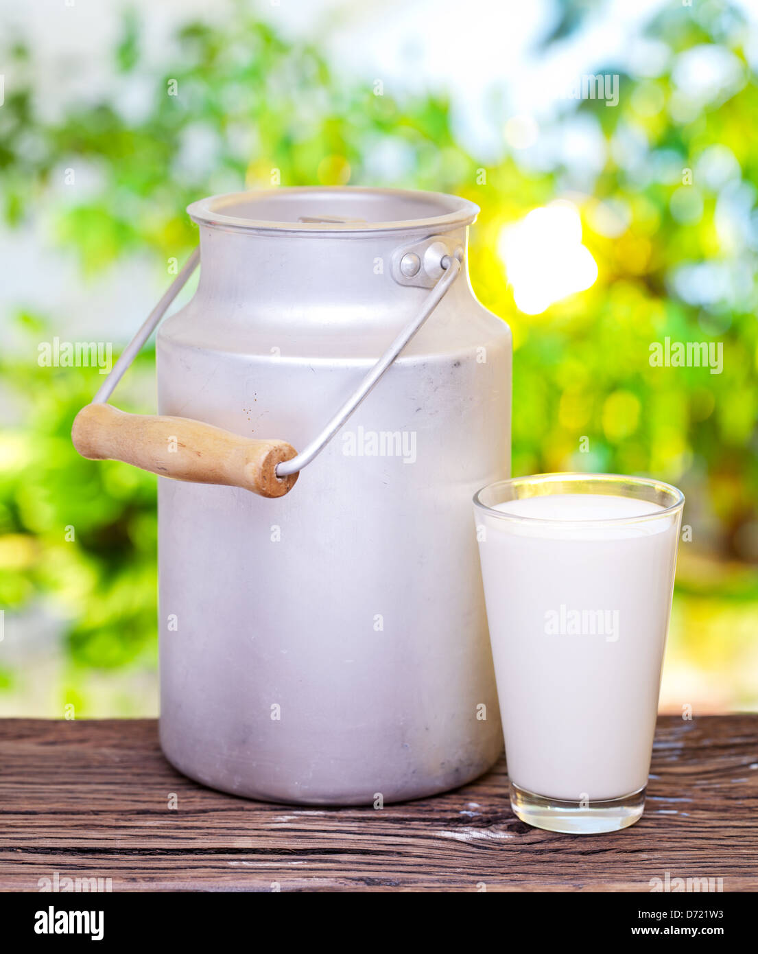 Milch in Aluminiumdose und Glas auf dem alten Holztisch im Freieneinstellung. Stockfoto