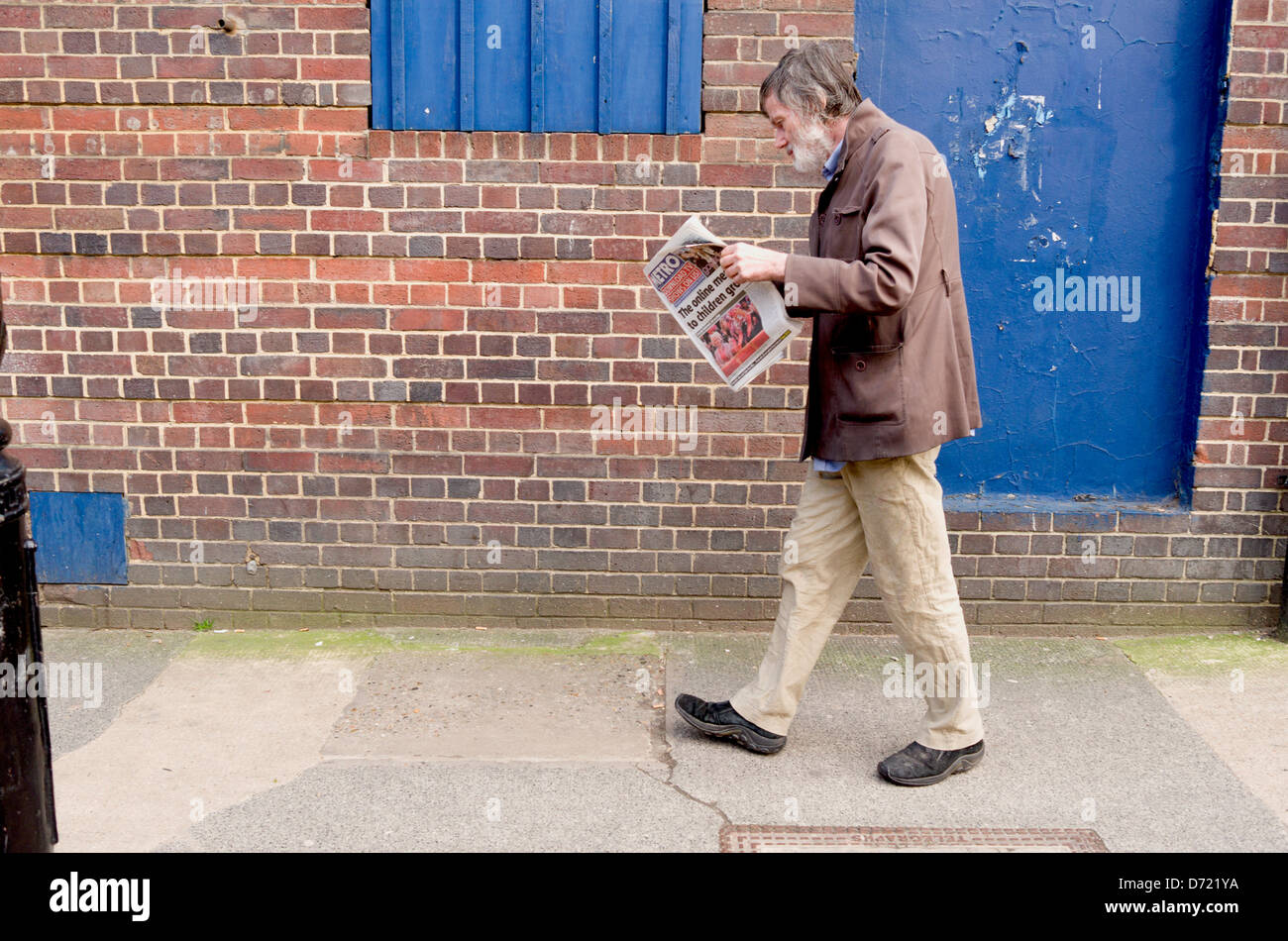 Mann zu Fuß während eine Zeitung zu lesen. Stockfoto