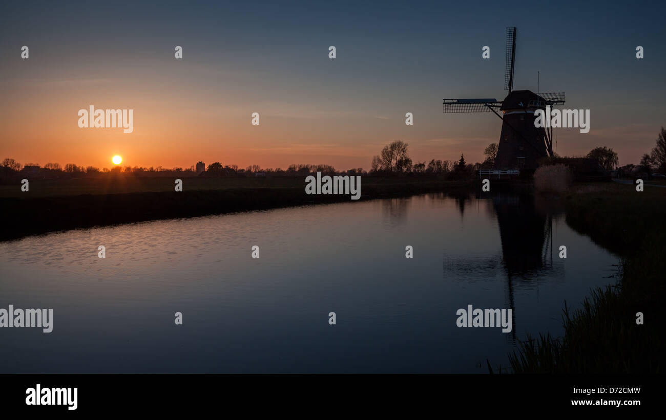 Niederländische Sonnenuntergang mit einer Windmühle spiegelt sich in einem Kanal Stockfoto