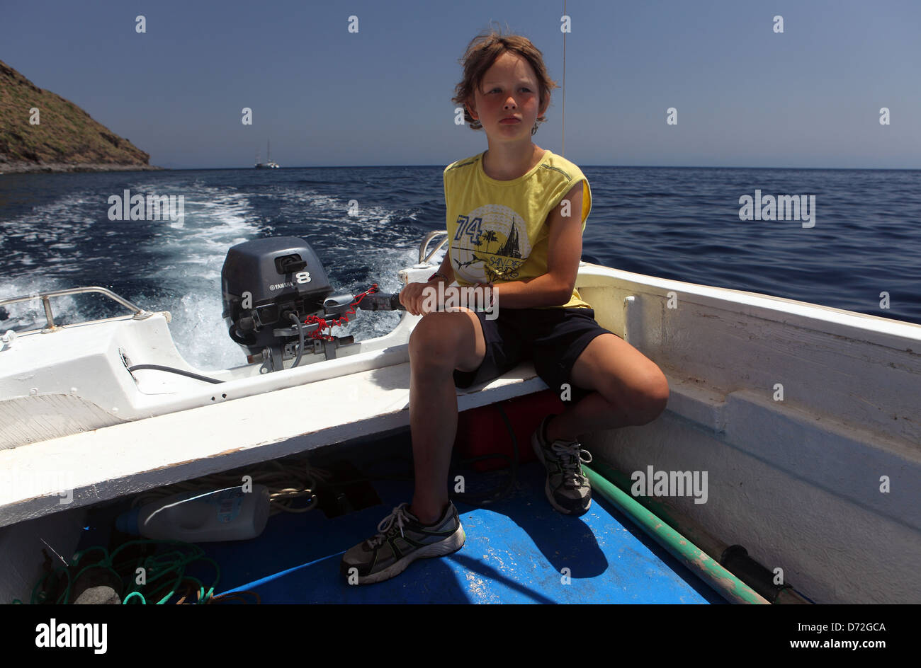 Alicudi, Italien, junge steuert ein Motorboot auf dem Meer Stockfoto