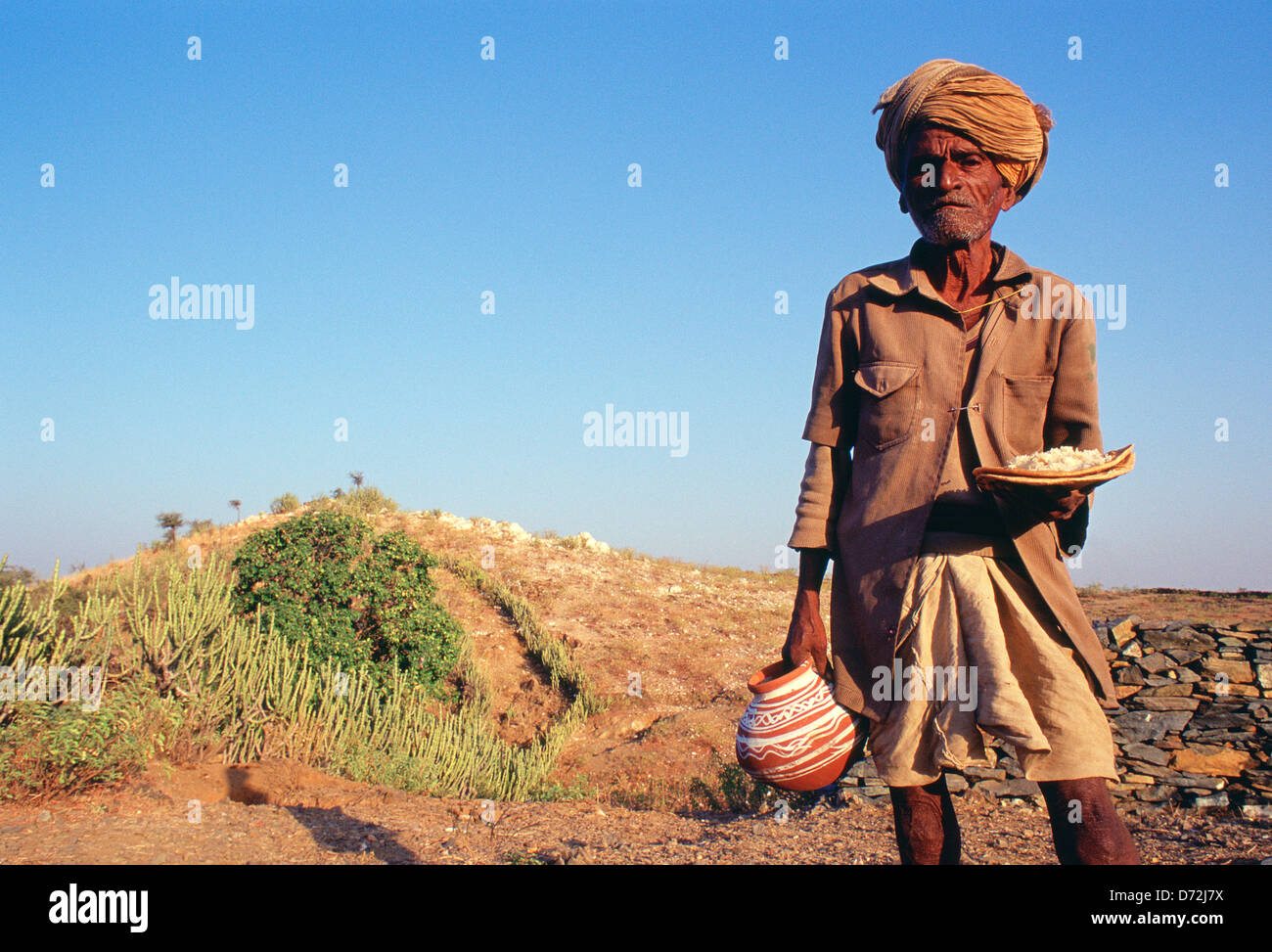 Ein Tribesman kommt aus einem Tod Gedenken mit Geschenken (irdenen Topf und Essen). Er gehört zum Stamm Bhil (Indien) Stockfoto
