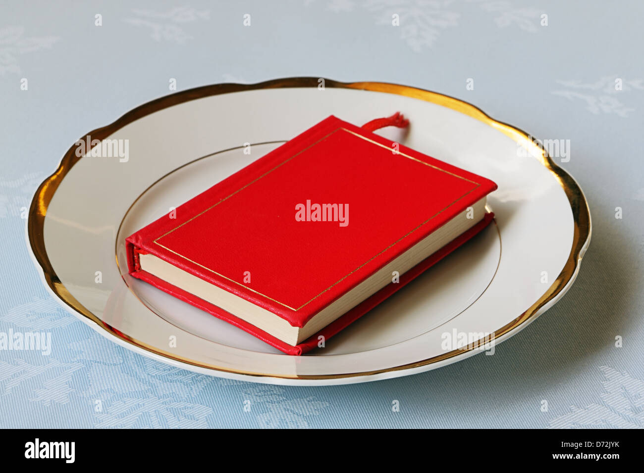 Rotes Buch auf weißem Porzellan mit goldener Borte Stockfoto