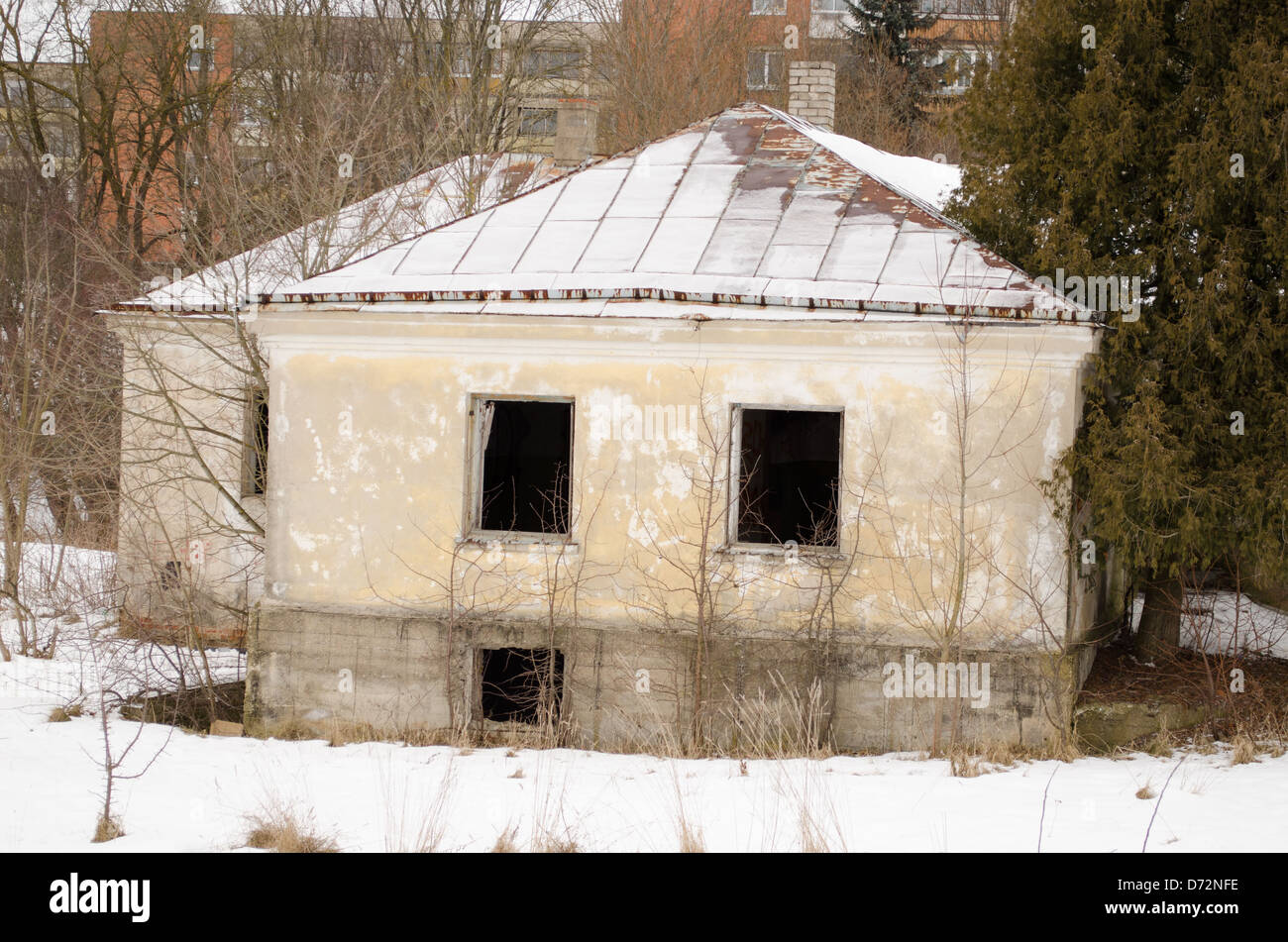 verlassene alte Mauerwerk Ziegelhaus mit zerbrochenen Fenstern in der Nähe von lebendigen Haus Bezirk im Winter. Stockfoto