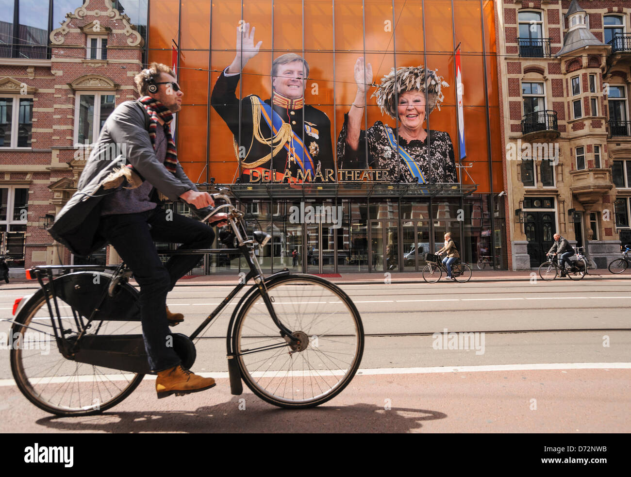 Niederlande, Amsterdam, 27 April 2013.A Radfahrer geht durch Porträts von Königin Beatrix der Niederlande und ihr Sohn, Kronprinz Willem-Alexander, 27. April 2013 vor einem Theater in Amsterdam angezeigt. Amsterdam, die Hauptstadt der Niederlande Koninginnedag am 30. April, bereitet das auch der Abdankung von Königin Beatrix und die Einsetzung der ihr ältester Sohn Willem-Alexander markieren wird. Alamy Live-Nachrichten Stockfoto