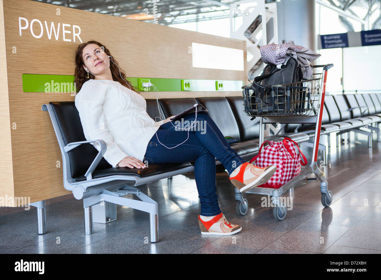 Weiblich, verbringt Zeit mit Tablet-pc in Flughafen-Lounge mit Hand-Gepäckwagen. Platz für Aufladen Ihres Handys und Geräte Stockfoto