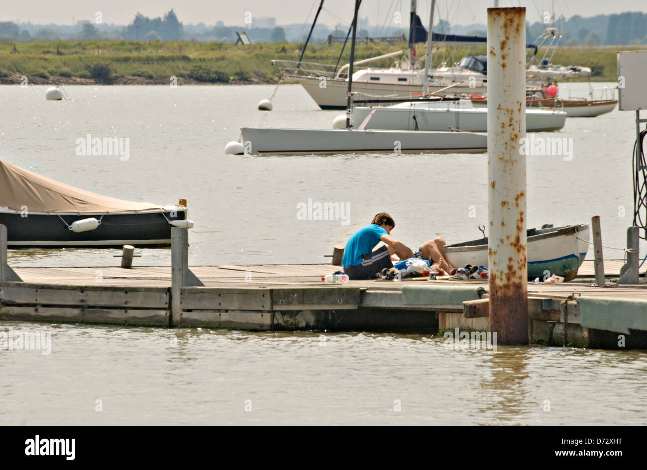 Zwei junge entspannt auf einen kleinen Holzsteg unter kleine Segelboote, blauer Himmel, Fluss-Steg. Stockfoto