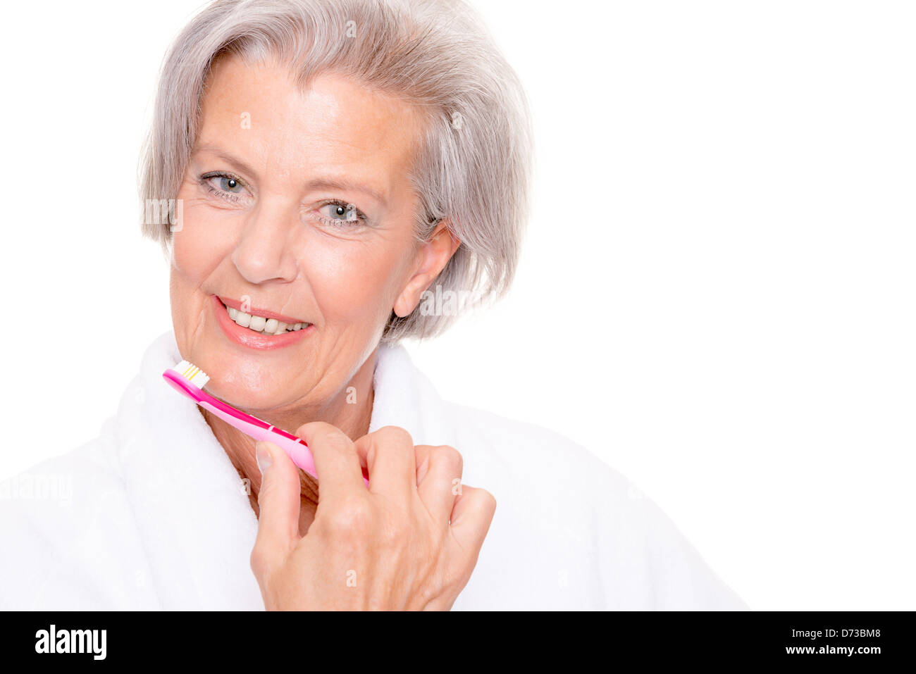Ältere Frau mit Zahnbürste vor weißem Hintergrund Stockfoto